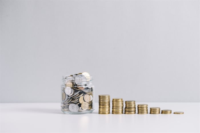 glass-jar-full-of-money-in-front-of-decreasing-stacked-coins-against-white-background (1).jpg